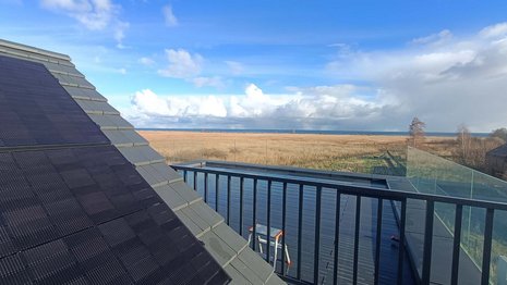 Solar modules on the rooftop of a house with a background sea view.
